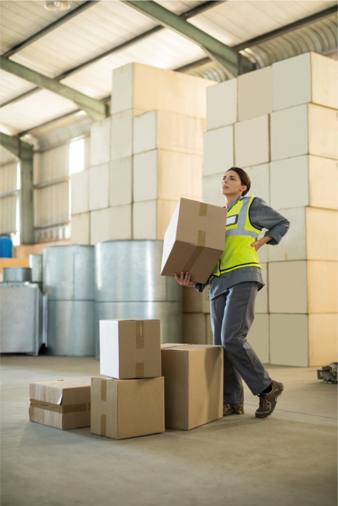 warehouse worker walking with box while holding their back